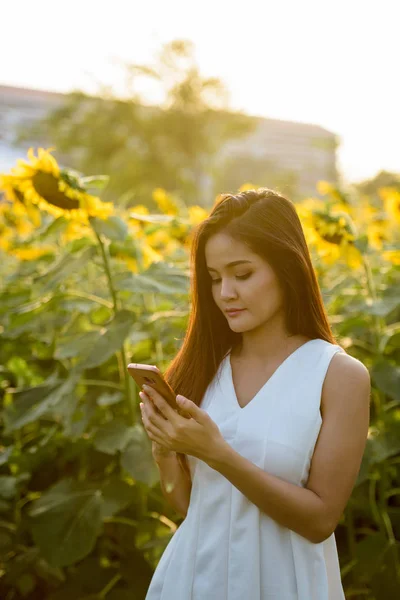 Joven hermosa mujer asiática utilizando el teléfono móvil en el campo de b — Foto de Stock