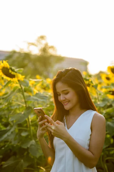 Joven mujer asiática feliz sonriendo mientras usa el teléfono móvil en el — Foto de Stock