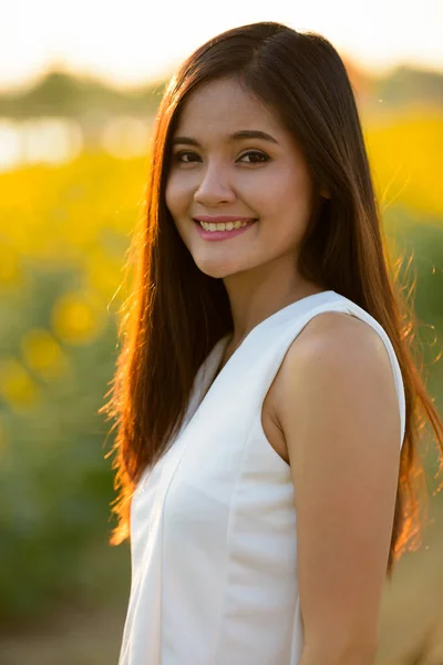 Joven mujer asiática feliz sonriendo contra el campo de florecimiento sunflo —  Fotos de Stock