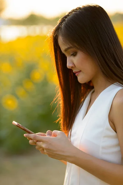 Joven hermosa mujer asiática utilizando el teléfono móvil contra el campo de — Foto de Stock