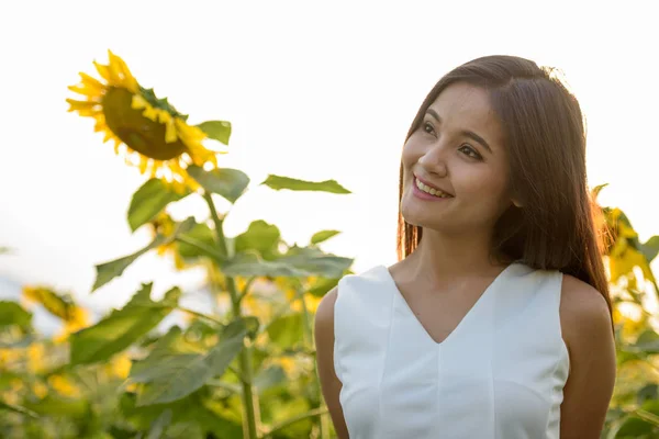 Joven mujer asiática feliz sonriendo mientras piensa en el campo de b —  Fotos de Stock