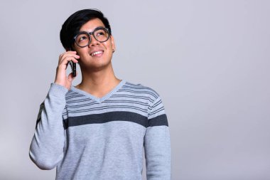Düşünceli mutlu Asya adam cep telefonu konuşurken gülümseyen
