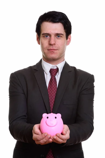 Studio shot of handsome businessman holding piggy bank — Stock Photo, Image