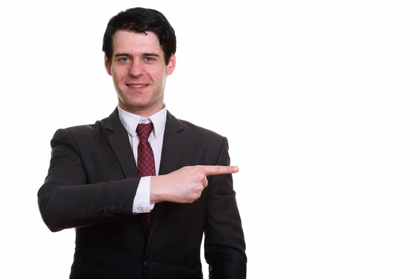 Студийный снимок счастливого бизнесмена, улыбающегося и указывающего пальцем — стоковое фото