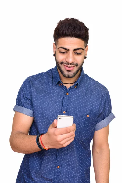 Estudio de tiro de joven feliz hombre indio utilizando el aislamiento del teléfono móvil —  Fotos de Stock