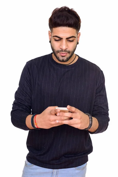 Studio shot of young handsome Indian man using mobile phone isol — Stock Photo, Image