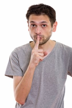Dudağında parmak olan genç adamın stüdyo fotoğrafı.