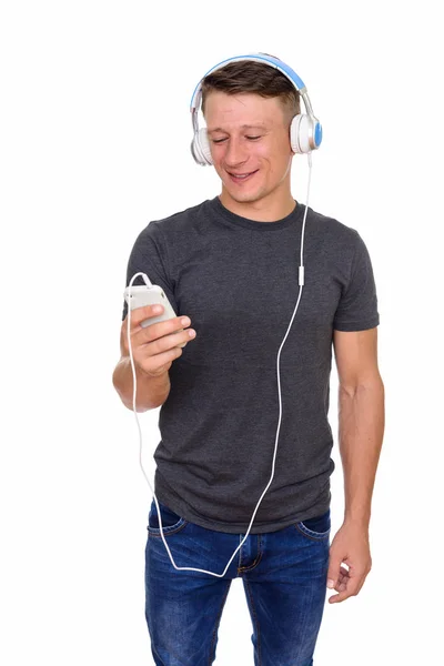 Studio shot of young happy Caucasian man holding mobile phone an — Stock Photo, Image