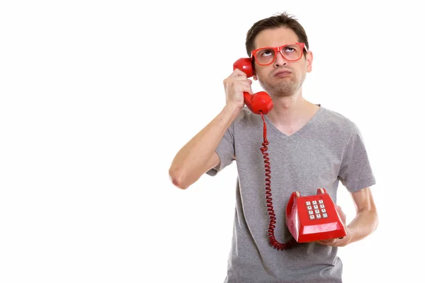 Estúdio tiro de jovem irritado falando no telefone antigo, enquanto — Fotografia de Stock