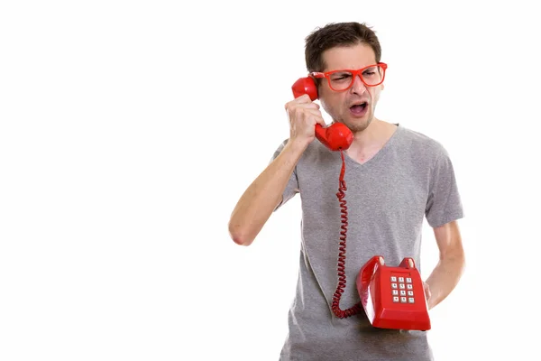 Estúdio tiro de jovem irritado falando no telefone antigo — Fotografia de Stock