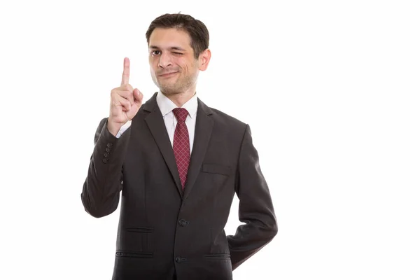 Studio shot of young businessman pointing finger up while winkin — Stock Photo, Image