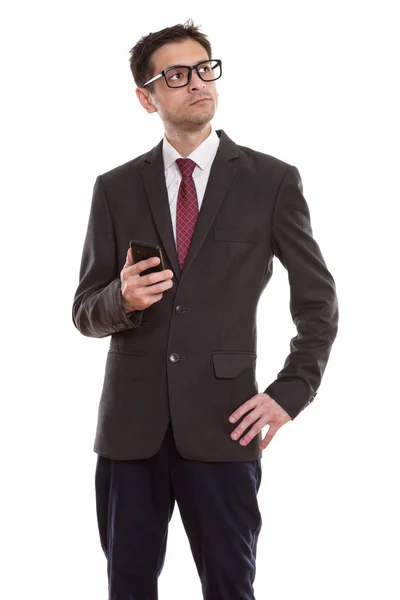 Studio shot of young businessman standing and thinking while hol — Stock Photo, Image