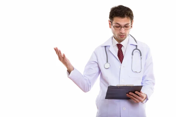 Studio shot of young man doctor reading on clipboard while gestu — Stock Photo, Image