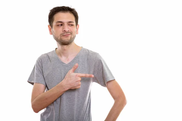 Estudio de un joven apuntando con el dedo y mirando a un lado — Foto de Stock