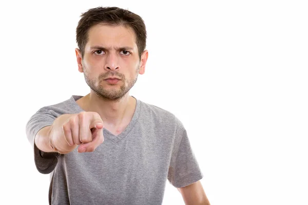 Studio shot of angry young man pointing at camera — Stock Photo, Image