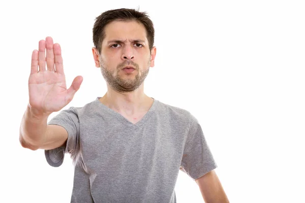 Studio shot of angry young man with stop hand sign — Stock Photo, Image