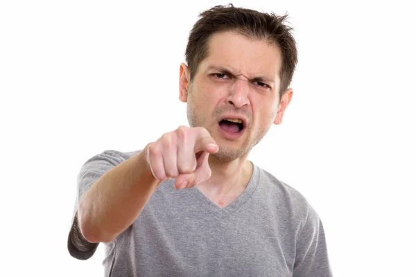 Studio shot of angry young man pointing at camera — Stock Photo, Image