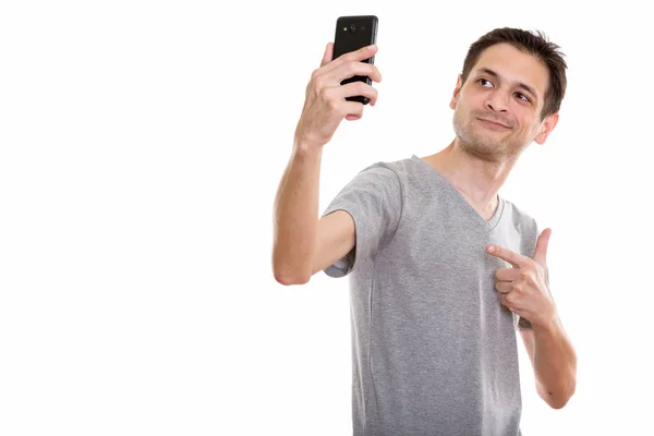 Studio shot van gelukkige jonge man die lacht terwijl het nemen van de selfie pictu — Stockfoto