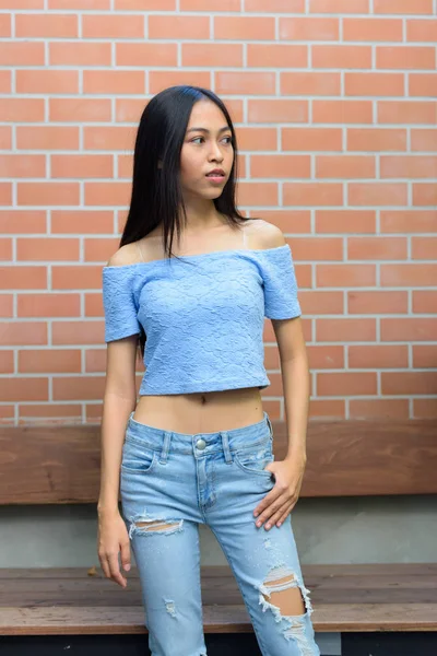 Молодих красивих азіатських Дівчинка-підліток стоячи розмірковуючи проти цегляна стіна — стокове фото