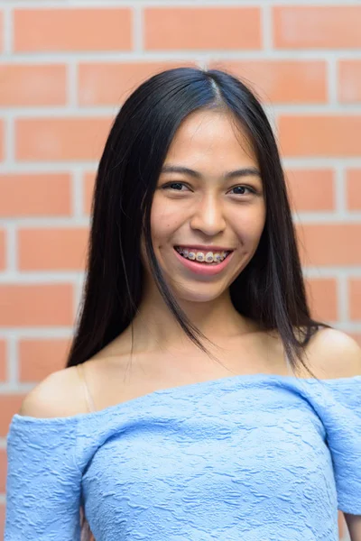 행복 한 아시아 십 대 소녀 벽돌 벽에 미소의 얼굴 — 스톡 사진