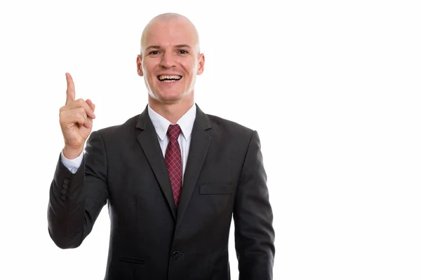 Studio shot of young happy bald businessman smiling while pointi — Stock Photo, Image