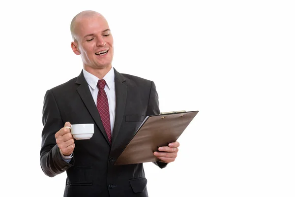 Studioaufnahme eines jungen glücklichen, glatzköpfigen Geschäftsmannes, der lächelt und liest — Stockfoto