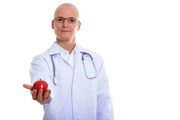 Estudio de tiro de joven calvo guapo médico dando manzana roja —  Fotos de Stock