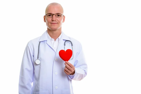 Студійний знімок молодого красивого лисого лікаря, який тримає червоне серце — стокове фото