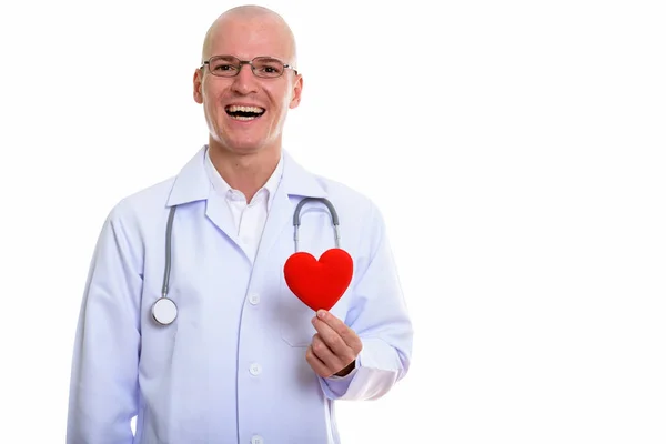 Estudio disparo de joven hombre calvo feliz médico sonriendo mientras sostiene —  Fotos de Stock