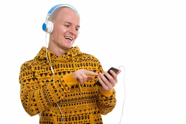 Studio skott av unga glada skallig man ler och använda mobila pho — Stockfoto
