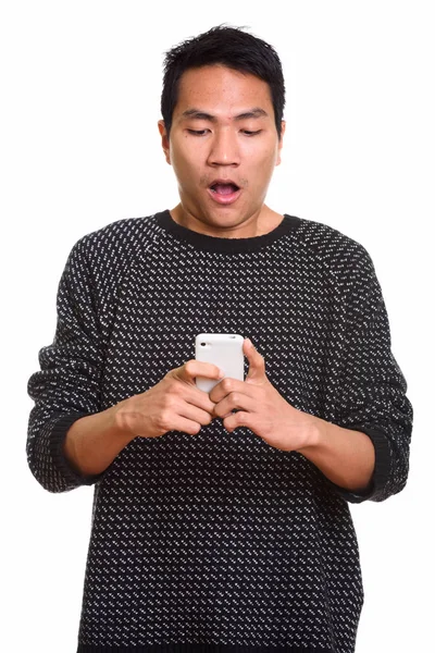 Студийный снимок молодого азиата, выглядящего шокированным при использовании мобиля — стоковое фото