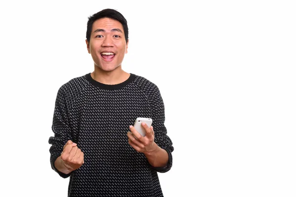 Estúdio tiro de jovem feliz asiático homem sorrindo enquanto segurando mobil — Fotografia de Stock