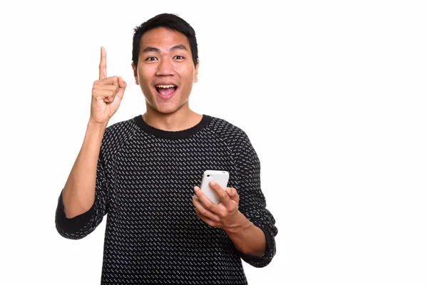 Estúdio tiro de jovem feliz asiático homem sorrindo enquanto segurando mobil — Fotografia de Stock