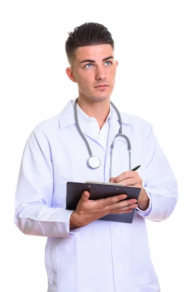 Joven hombre guapo médico escribiendo en el portapapeles mientras piensa — Foto de Stock