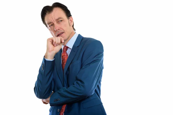 Studio shot of mature angry businessman thinking with hand on ch — Stock Photo, Image