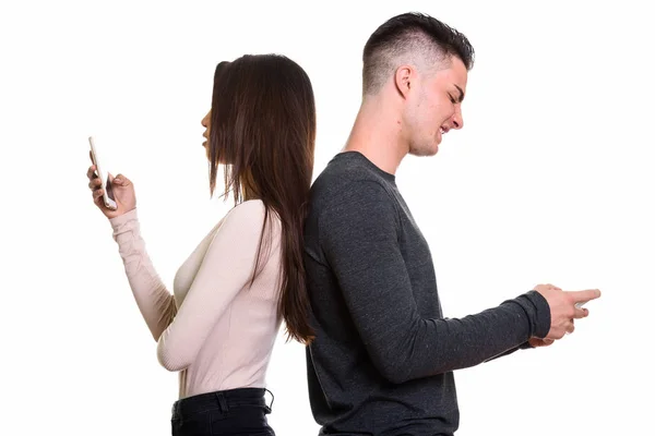 Visão de perfil de jovem casal irritado usando telefone celular com costas — Fotografia de Stock