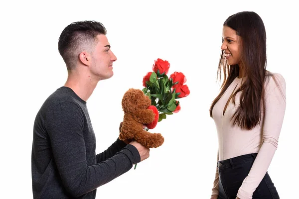 Молода щаслива пара посміхається і закохана в чоловіка, що дарує червоні троянди — стокове фото