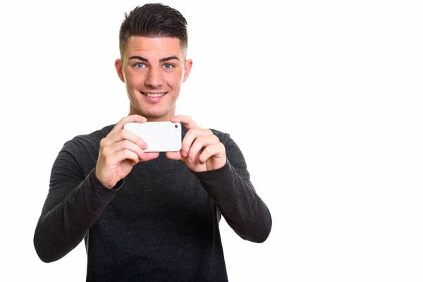 Onnellinen komea mies hymyilee ottaessaan kuvan matkapuhelimella — kuvapankkivalokuva