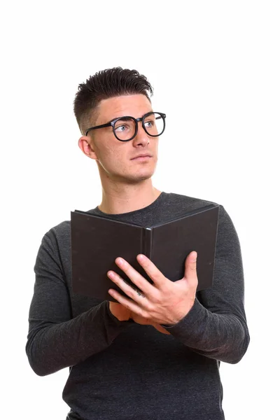 Estudio disparo de joven guapo sosteniendo libro mientras pensaba —  Fotos de Stock