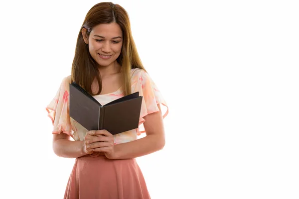 Студийный снимок счастливой молодой красивой женщины, улыбающейся во время чтения — стоковое фото