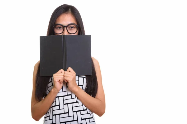 Молодая азиатская девочка-ботаник прячется за книгой — стоковое фото