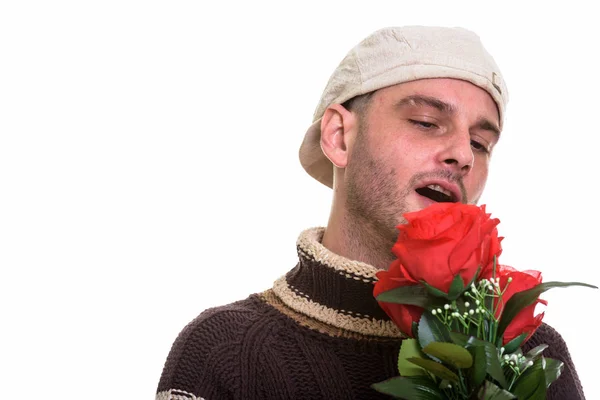 Studio záběr mladého muže drží a při pohledu na červené růže — Stock fotografie