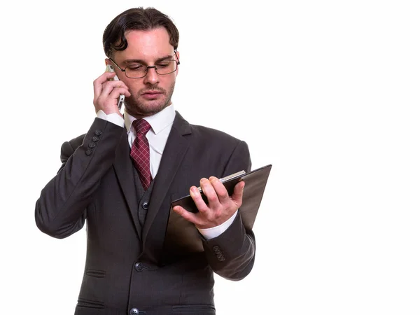 Studio shot van jonge zakenman praten op mobiele telefoon terwijl r — Stockfoto