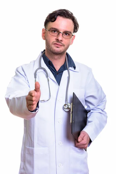 Студійний знімок молодого лікаря, який тримає кишеню, даючи h — стокове фото