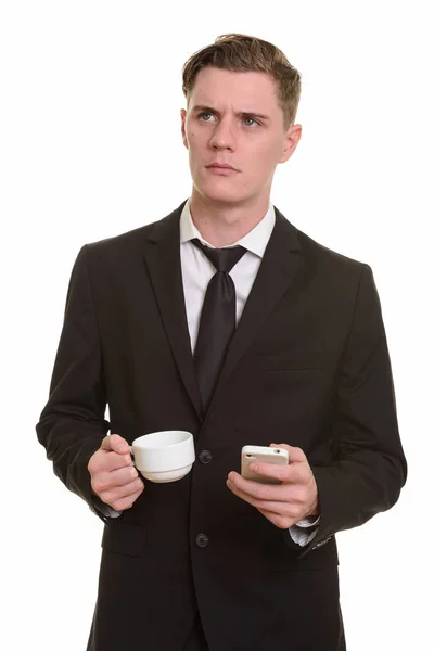 Young handsome Caucasian businessman thinking while holding mobi — Stock Photo, Image