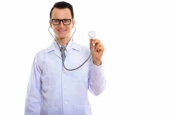 Studio shot of young happy man doctor smiling while using stetho — Stock Photo, Image