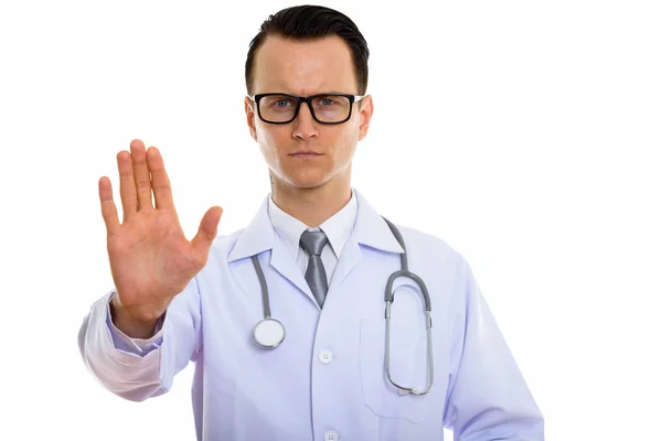 Studio shot of young handsome man doctor with stop hand gesture — Stock Photo, Image