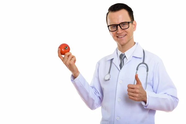 Studio shot of young happy man doctor smiling while holding red — Stock Photo, Image
