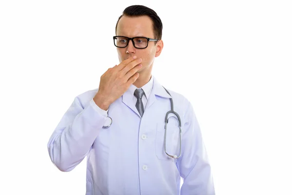 Studio shot of young handsome man doctor looking shocked while c — Stock Photo, Image