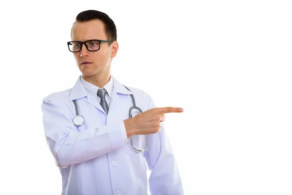 Студийный снимок молодого разъяренного врача, указывающего на бок — стоковое фото